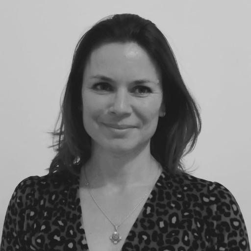 Saskia Ruijsink- A black and white picture of a white woman with dark hair and wearing a necklace, shirt and cover up. She is smiling into the camera. 