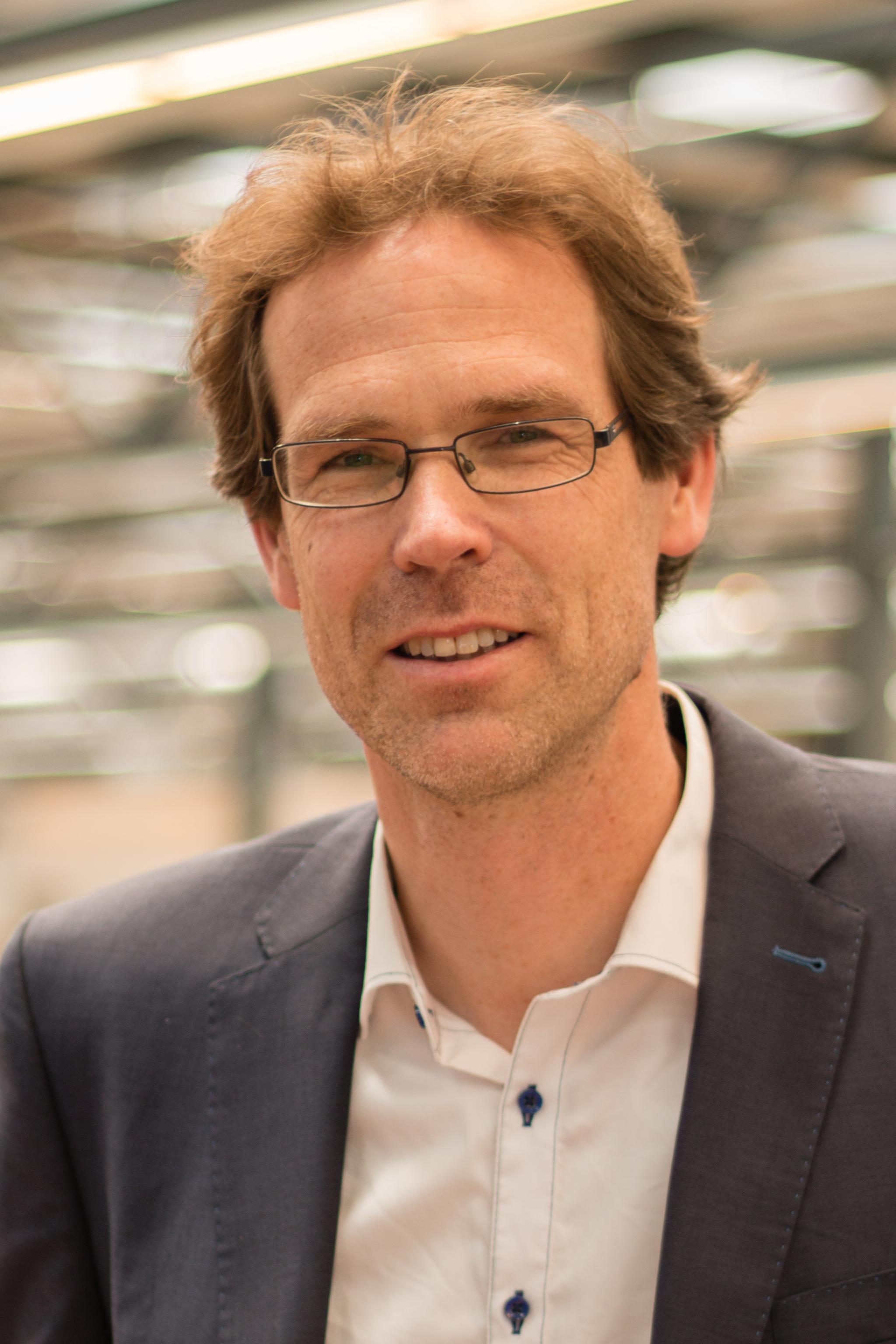 Victor Scholten: A white man with blond hair and glasses smiling into the camera. 